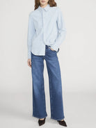 Person wearing a light blue shirt and blue jeans on a white background