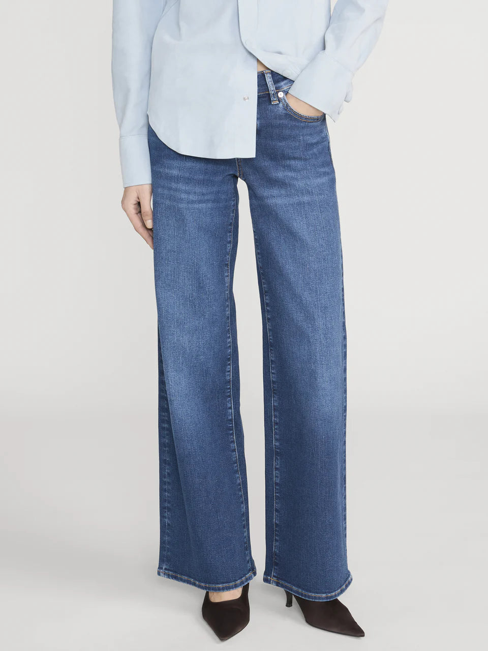 Person wearing blue jeans and a light blue shirt on a white background