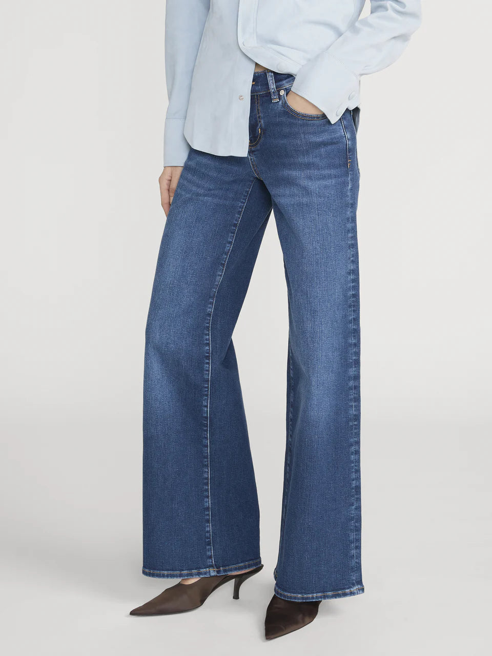 Person wearing blue flared jeans on a white background