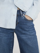 Person wearing blue jeans and a light blue jacket on a plain background