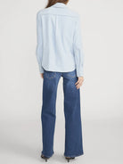 Person wearing a light blue shirt and blue jeans on a white background