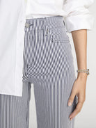 Person wearing black and white striped pants with a white shirt.