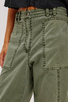 Close-up of olive green pants with a plain background