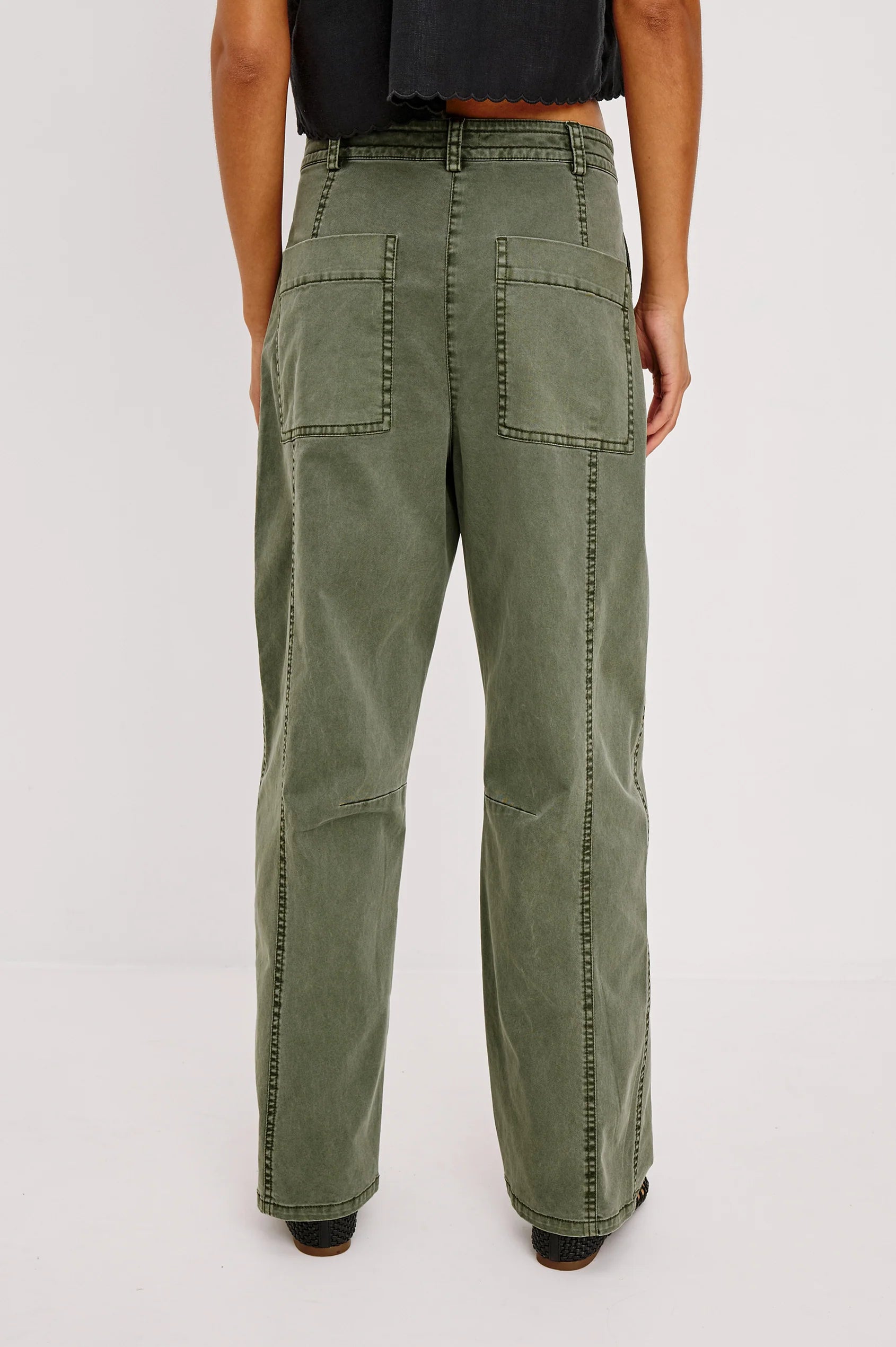Person wearing olive green cargo pants on a white background
