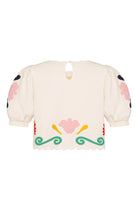 Cream-colored blouse with floral and decorative patterns on a white background