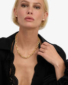 Woman wearing a gold chain necklace with a plain background