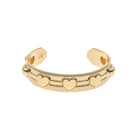 A gold cuff bracelet featuring a row of heart motifs and small raised heart accents, shown on a plain white background.