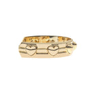 A gold-plated metal ring with a wide, geometric band featuring three raised heart-shaped motifs and horizontal channel details, shown against a plain white background.
