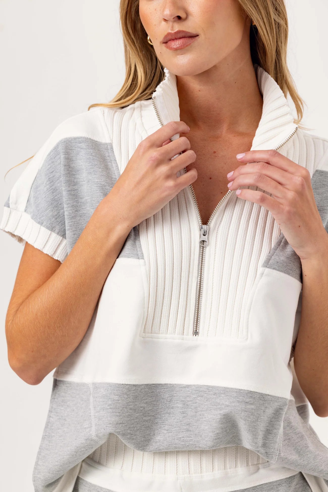 Woman wearing a white and gray striped sweater with a zipper.