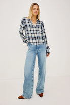 Woman wearing a plaid shirt and blue jeans on a white background