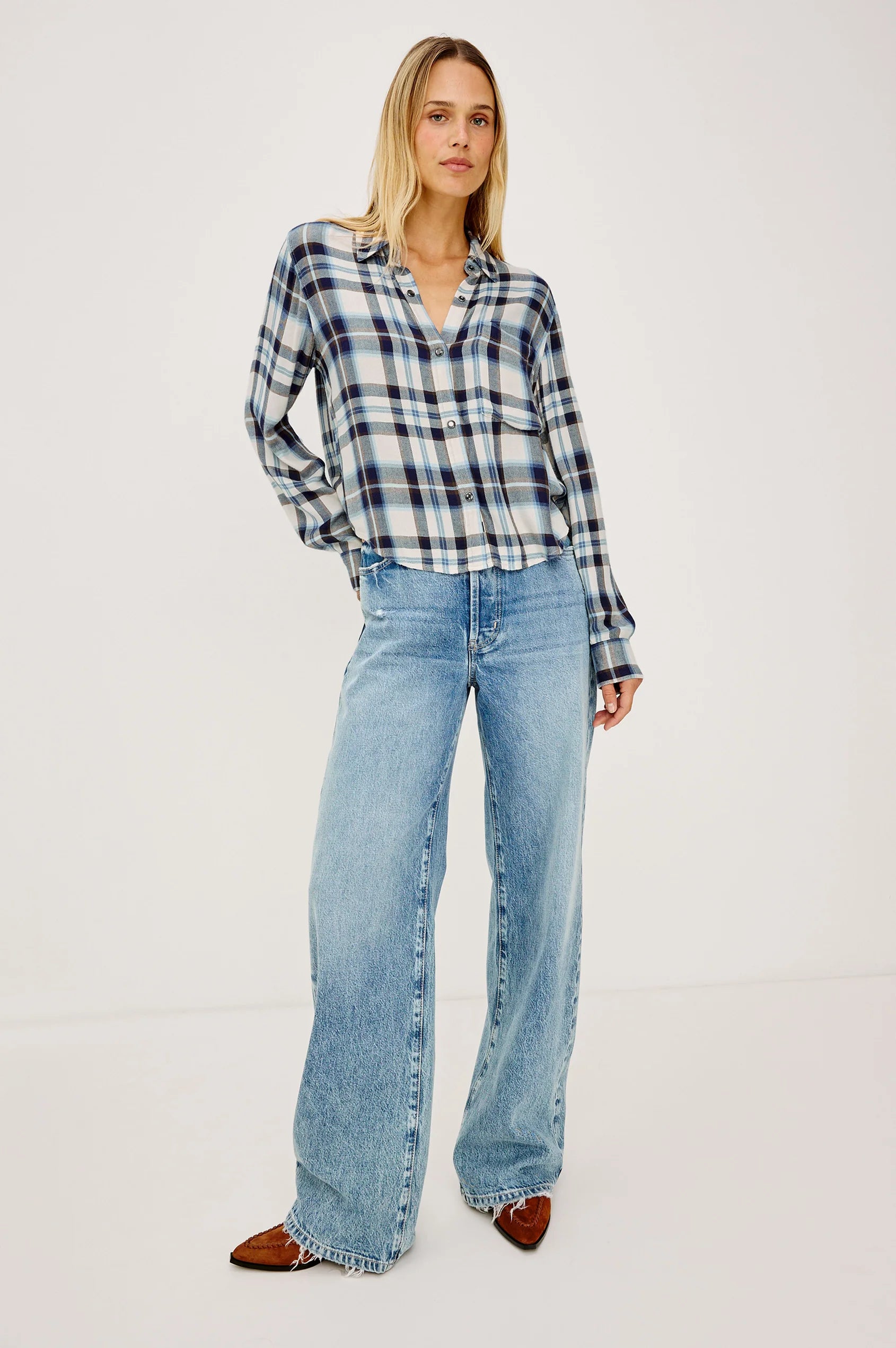 Woman wearing a plaid shirt and blue jeans on a white background