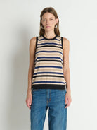Woman wearing a striped tank top and jeans against a plain background