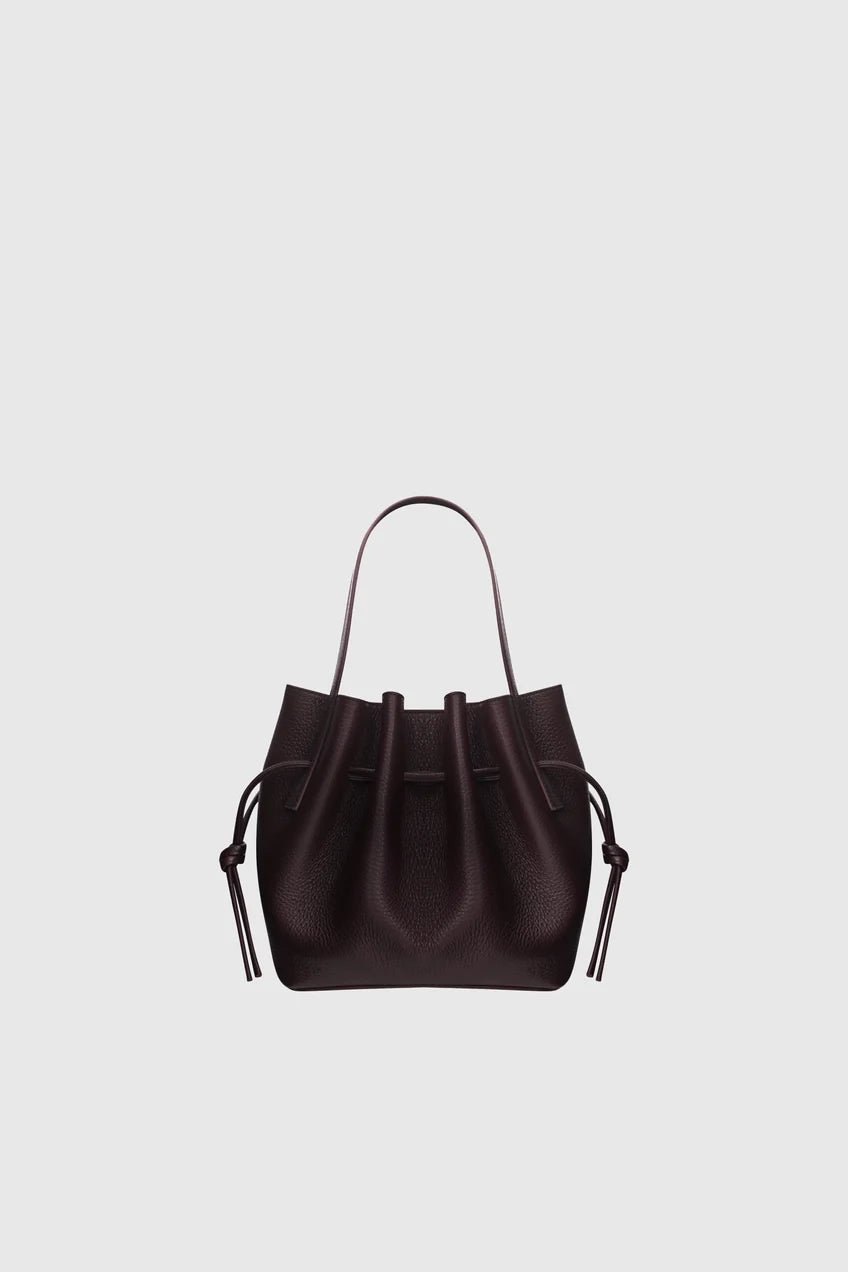 A dark brown leather bucket bag with a top handle and drawstring ties, centered on a light gray background.