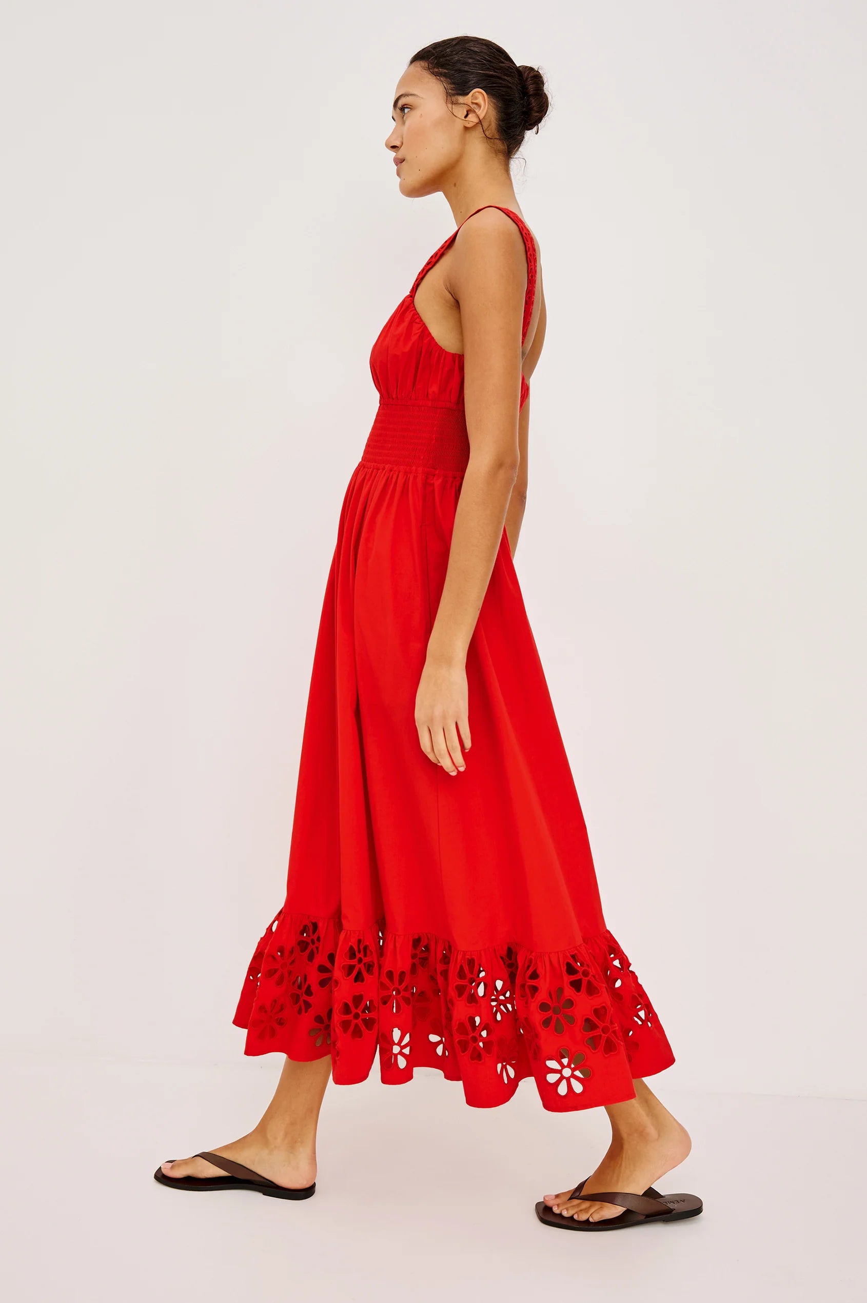Woman wearing a red dress with floral details on a white background