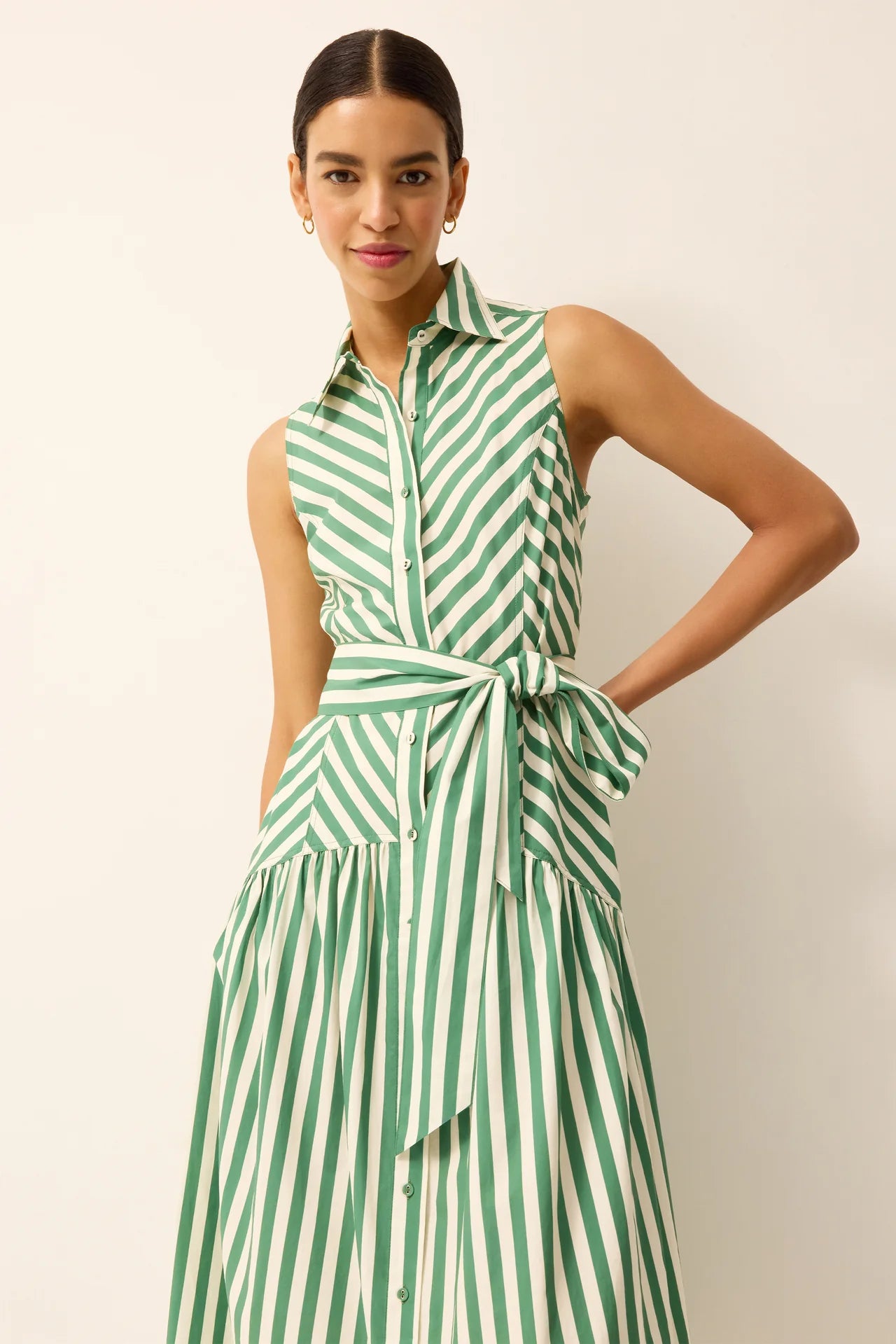 Woman wearing a green and white striped dress against a plain background