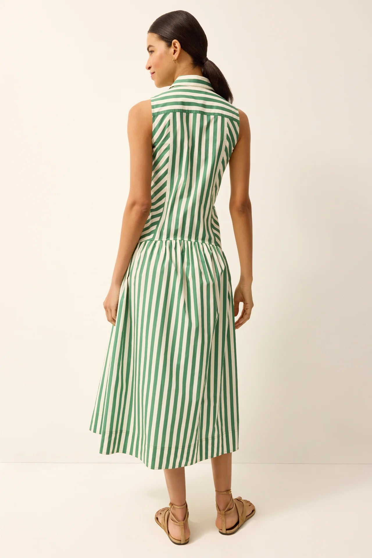 Woman wearing a green and white striped dress against a plain background