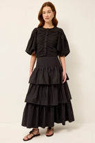 Woman wearing a black tiered dress against a white background