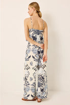 Woman wearing a floral jumpsuit on a plain background