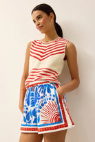 Woman wearing a red and white striped sleeveless top and a blue and white patterned skirt against a plain background.