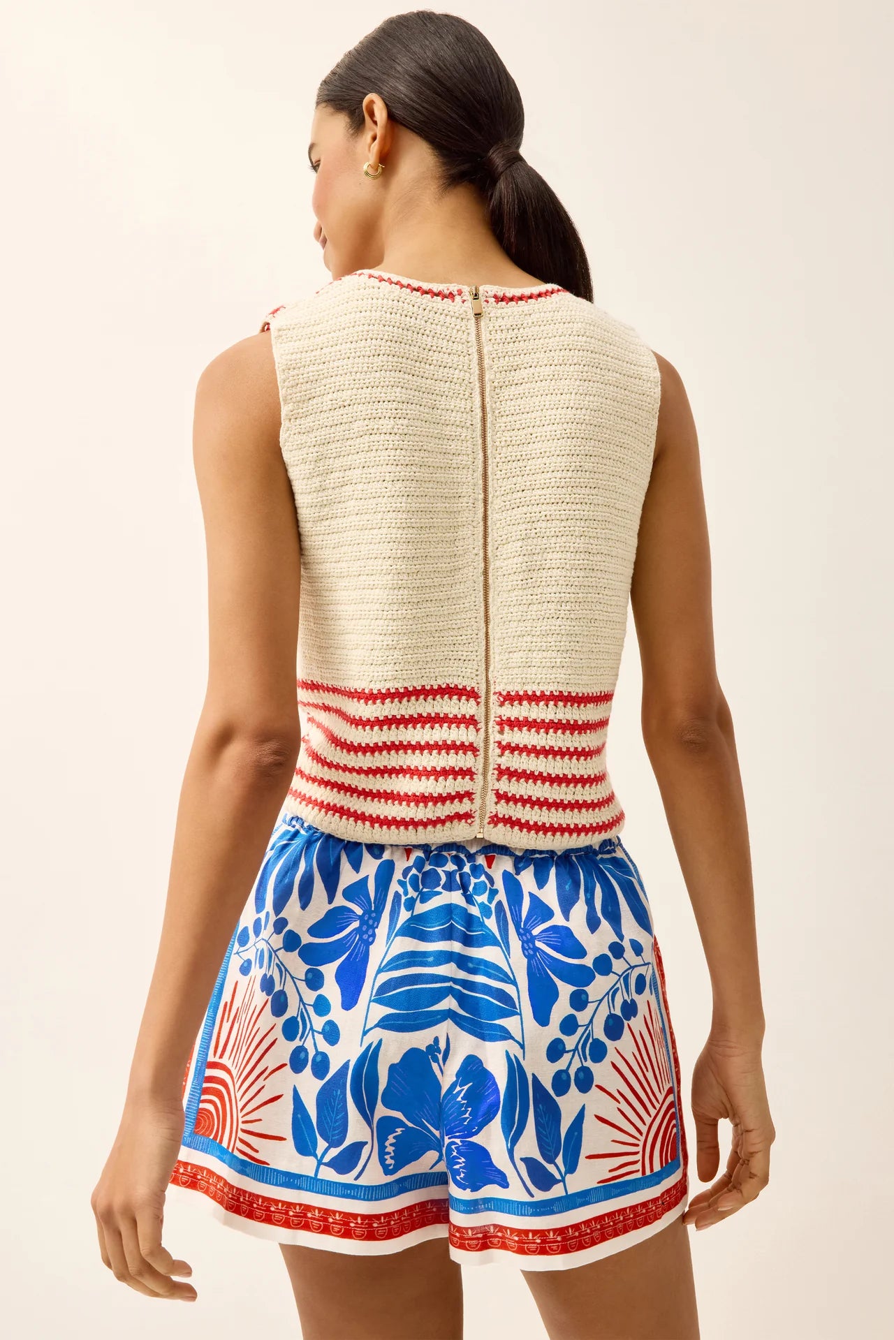Woman wearing a sleeveless top with a striped pattern and a colorful skirt on a beige background