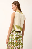 Woman wearing a white sleeveless top with green stripes and a floral skirt on a white background