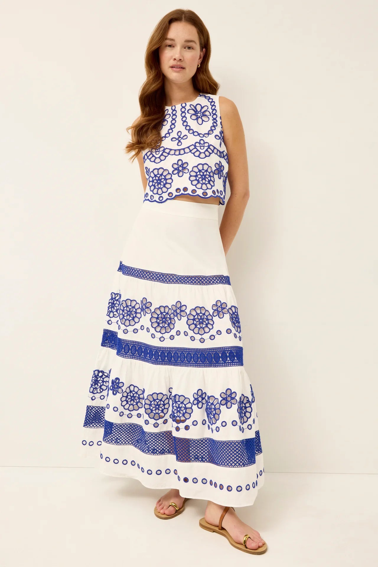 Woman wearing a white dress with blue floral patterns on a plain background