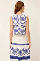 White dress with blue floral embroidery on a plain background