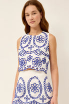Woman wearing a white dress with blue floral patterns on a plain background