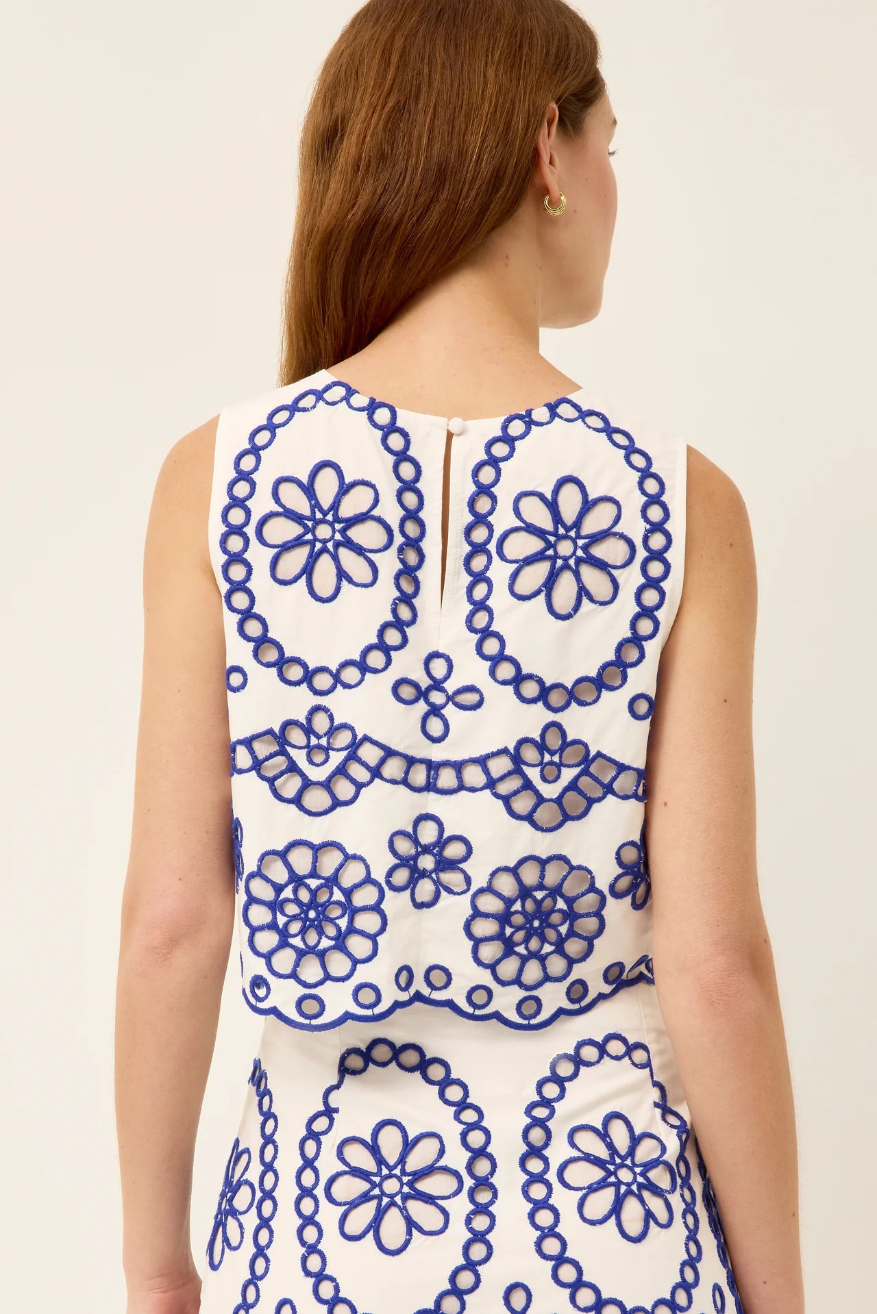 Woman wearing a sleeveless dress with blue floral patterns on a white background