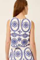 Woman wearing a sleeveless dress with blue floral patterns on a white background
