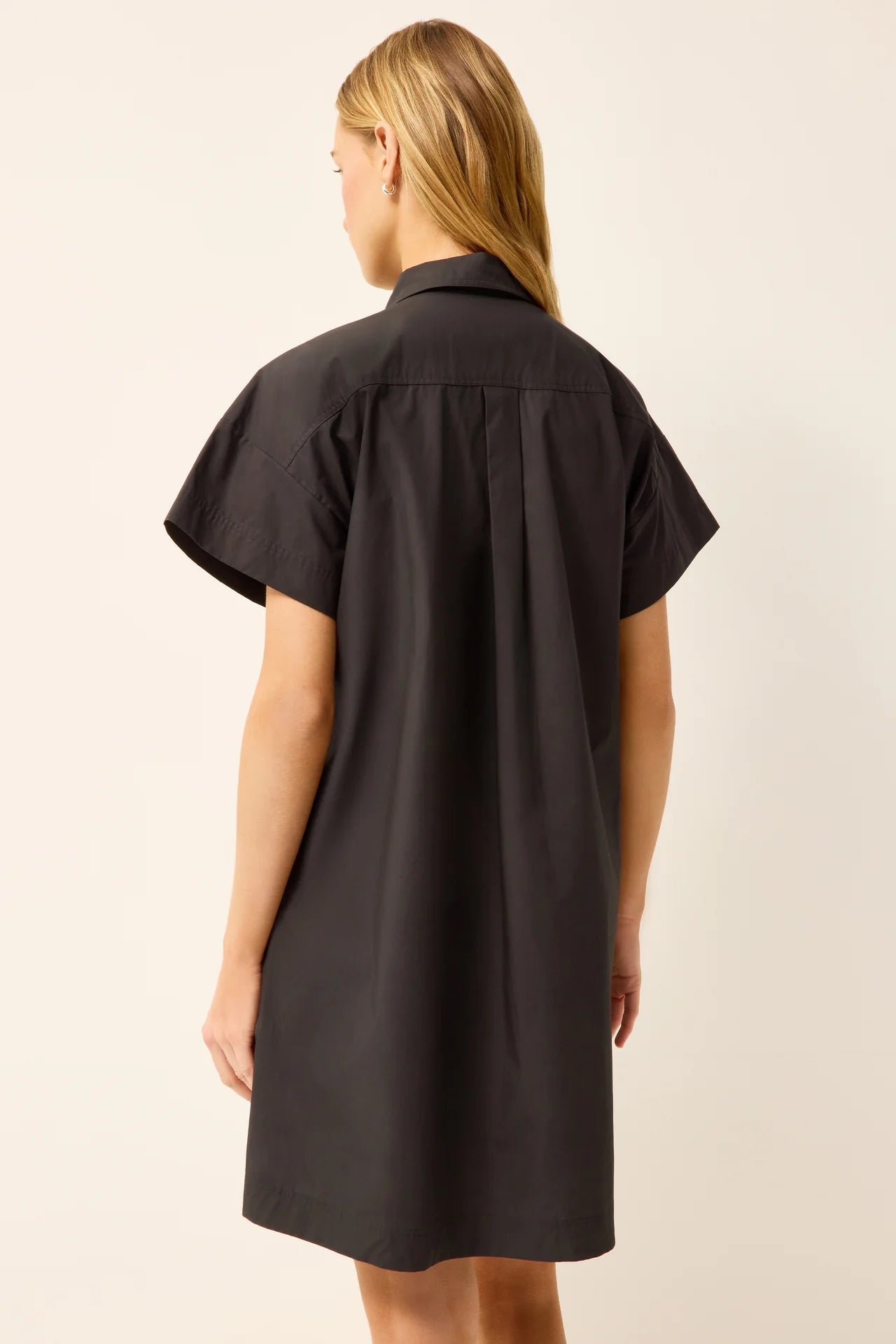 Woman wearing a black shirt dress against a plain background
