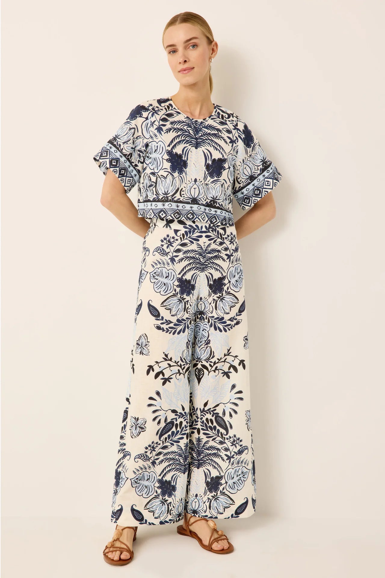 Woman wearing a blue and white floral dress against a beige background