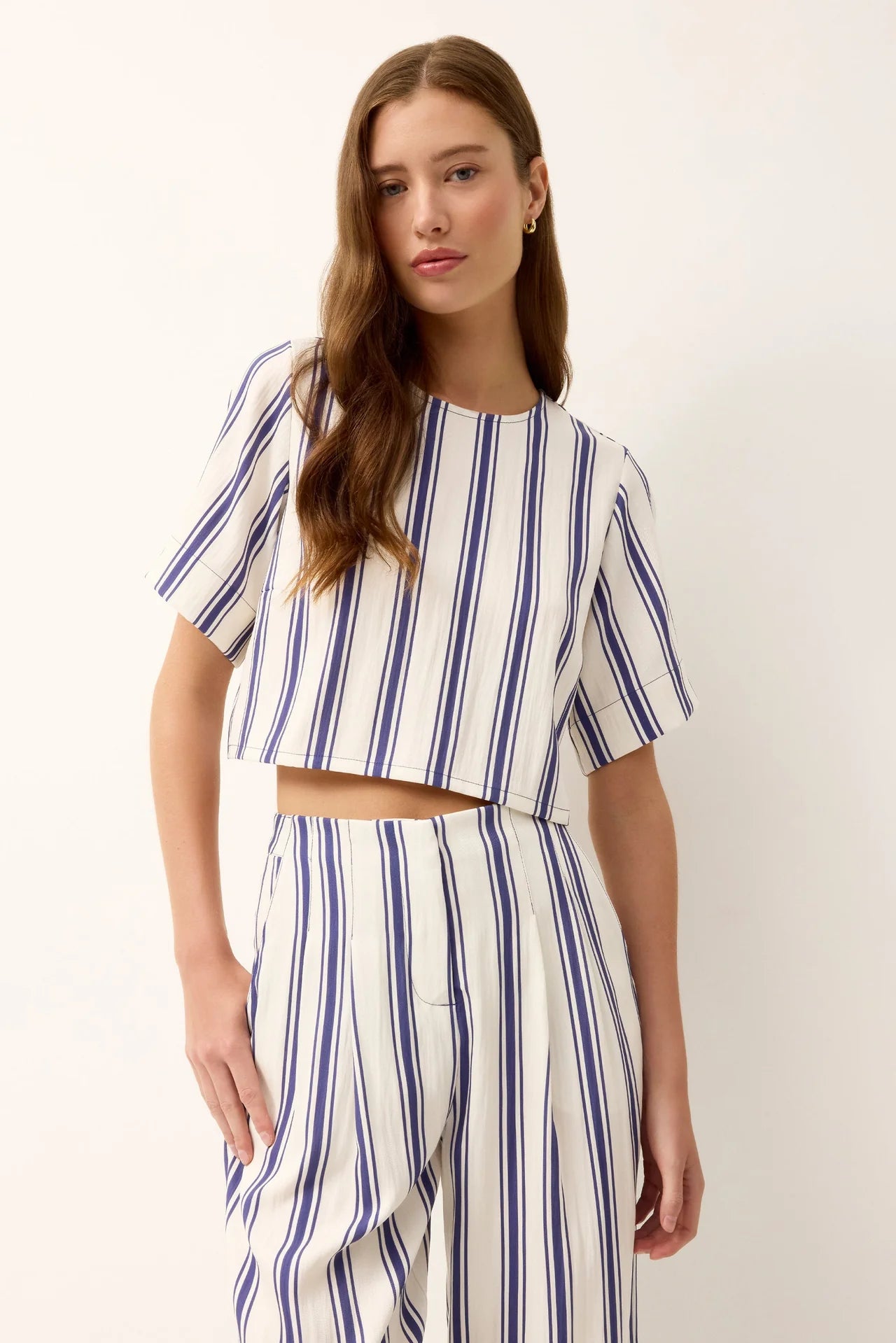 Woman wearing a blue and white striped dress against a white background