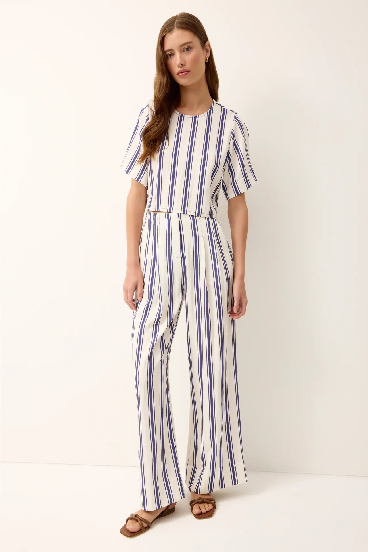 Woman wearing a blue and white striped jumpsuit on a white background