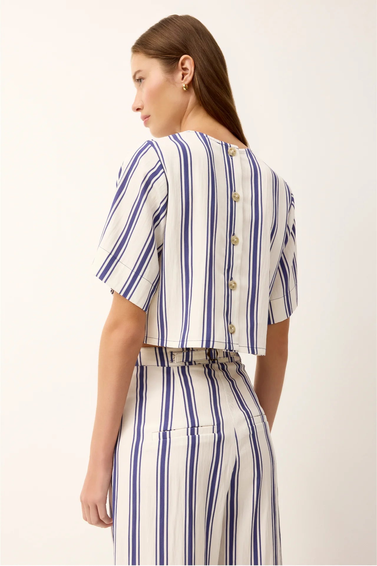 Woman wearing a blue and white striped outfit on a plain background
