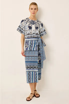 Woman wearing a blue and white patterned dress on a plain background