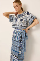 Woman wearing a blue and white patterned outfit against a plain background