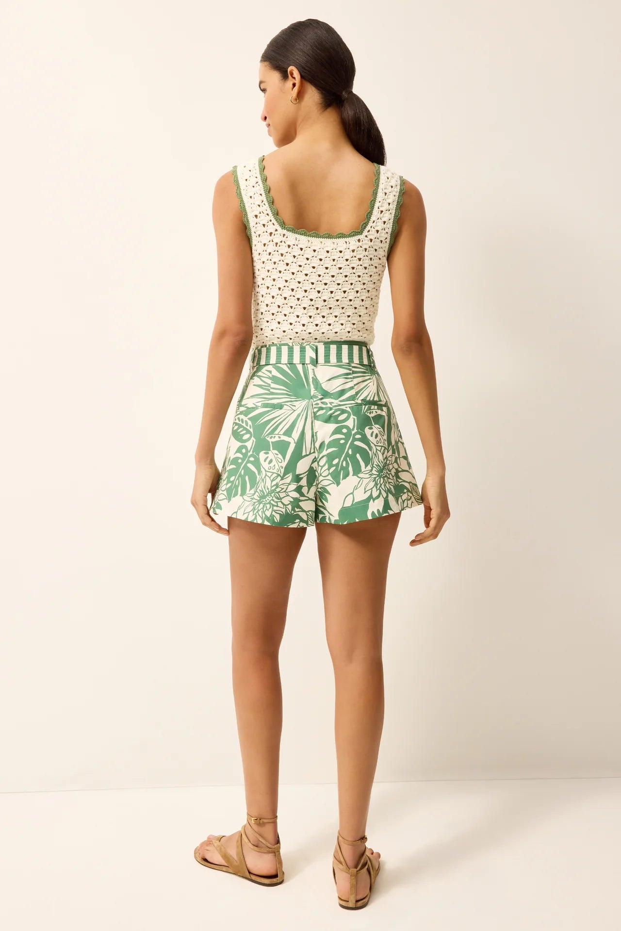 Woman wearing a sleeveless top and leaf-patterned shorts on a white background