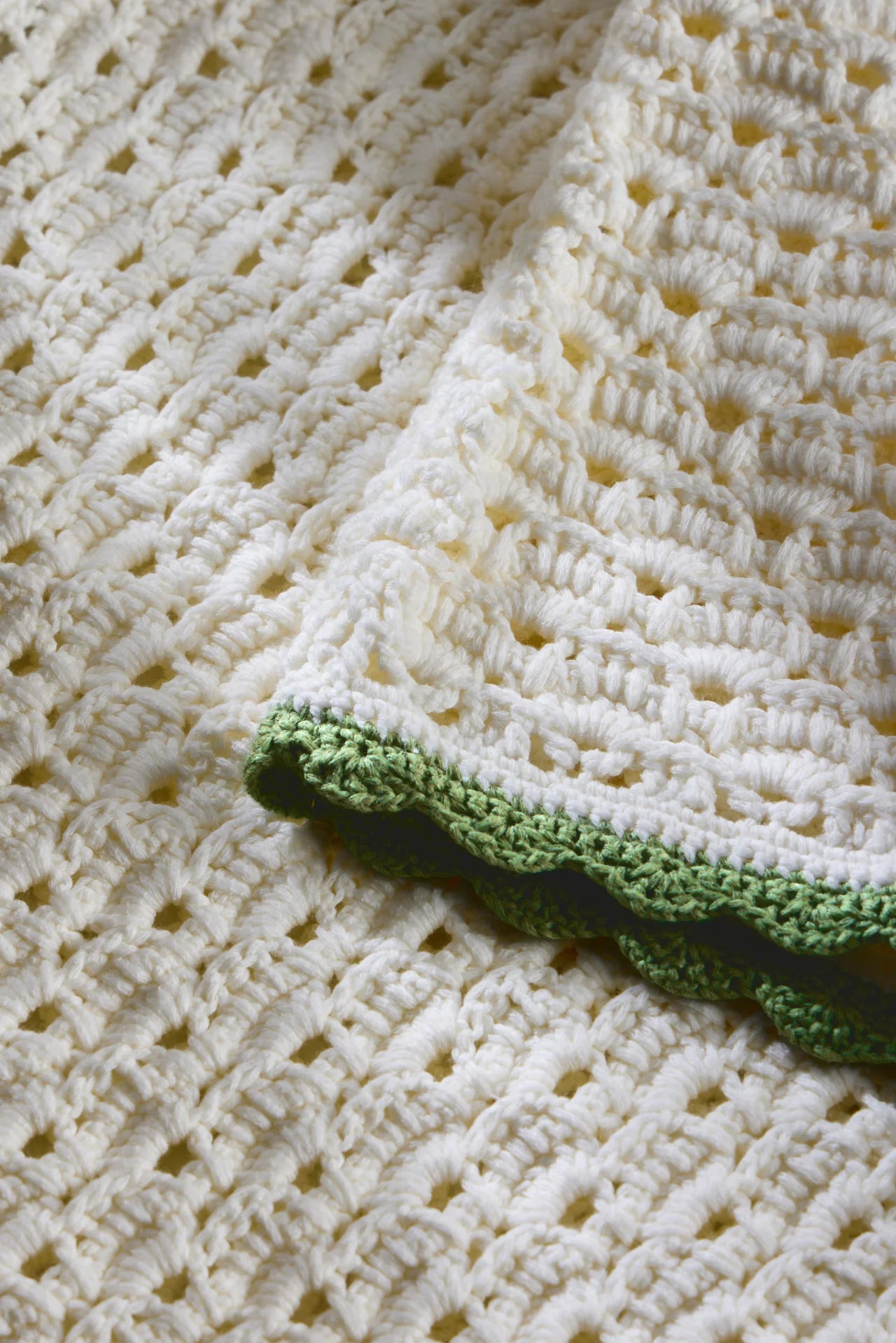 Close-up of a crocheted blanket with a green border