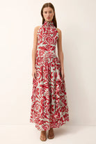 Woman wearing a sleeveless dress with red and white floral pattern on a white background
