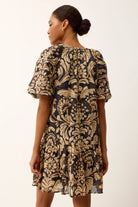 Woman wearing a black and gold floral dress on a white background