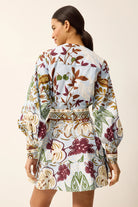 Woman wearing a long-sleeve dress with a floral pattern on a beige background