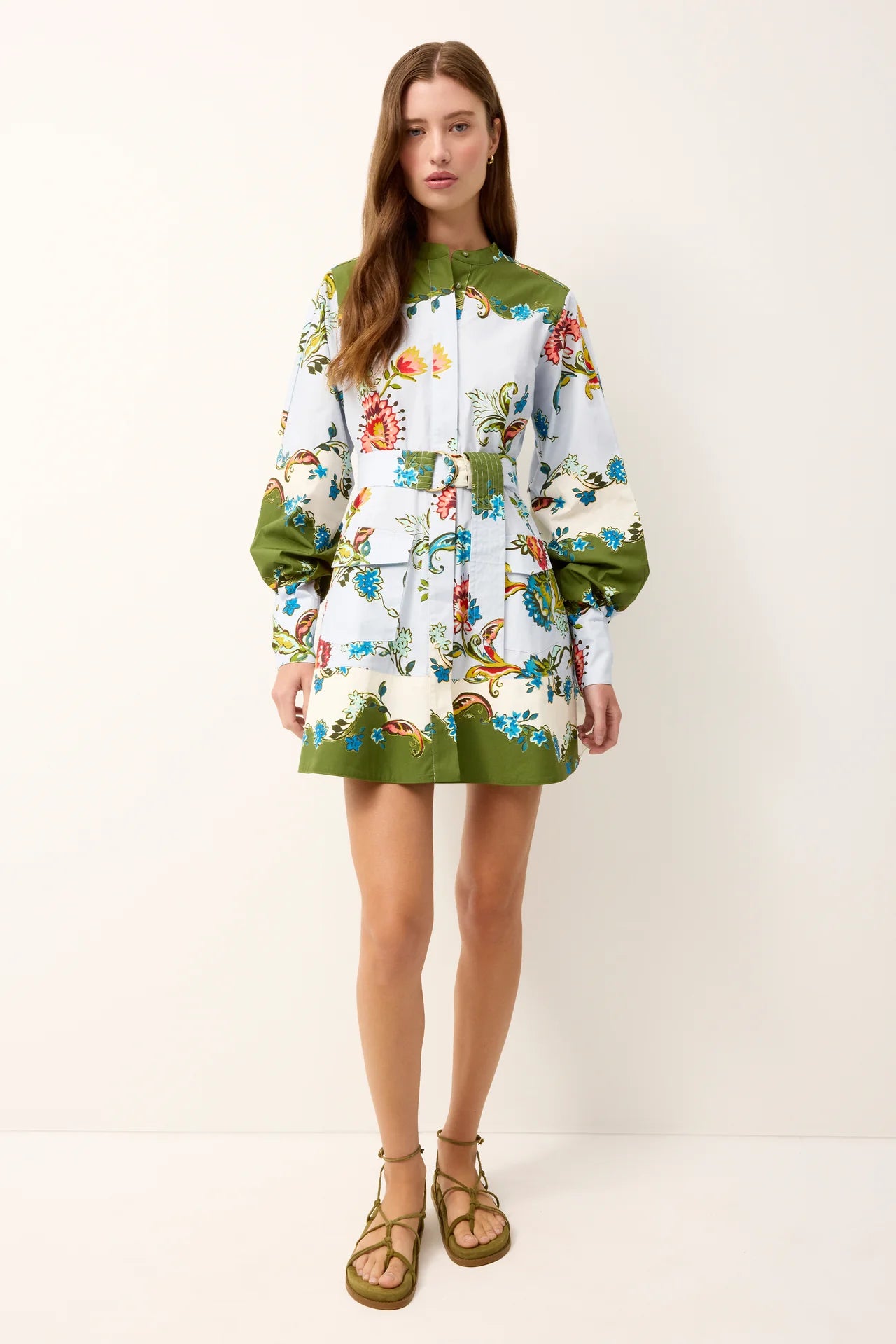 Woman wearing a floral dress with green accents on a white background