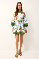 Woman wearing a floral dress with green accents on a white background