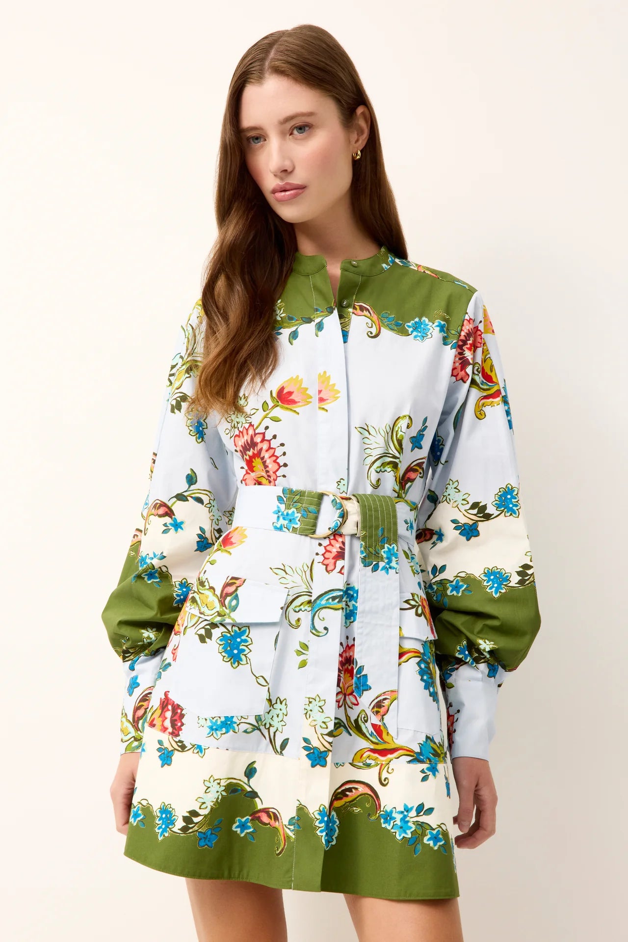 Woman wearing a colorful floral dress with green accents on a white background