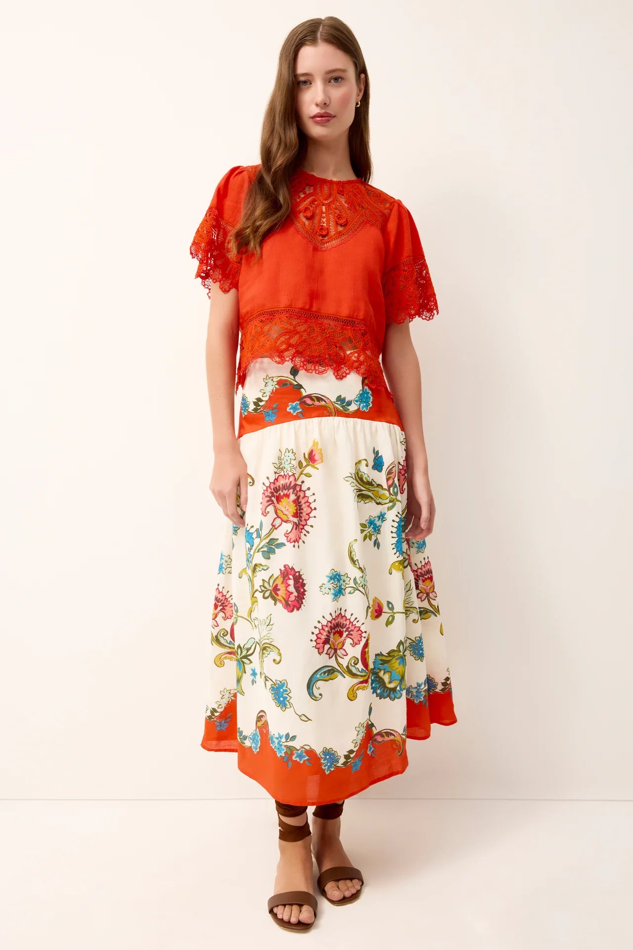 Woman wearing a red top and floral skirt on a white background
