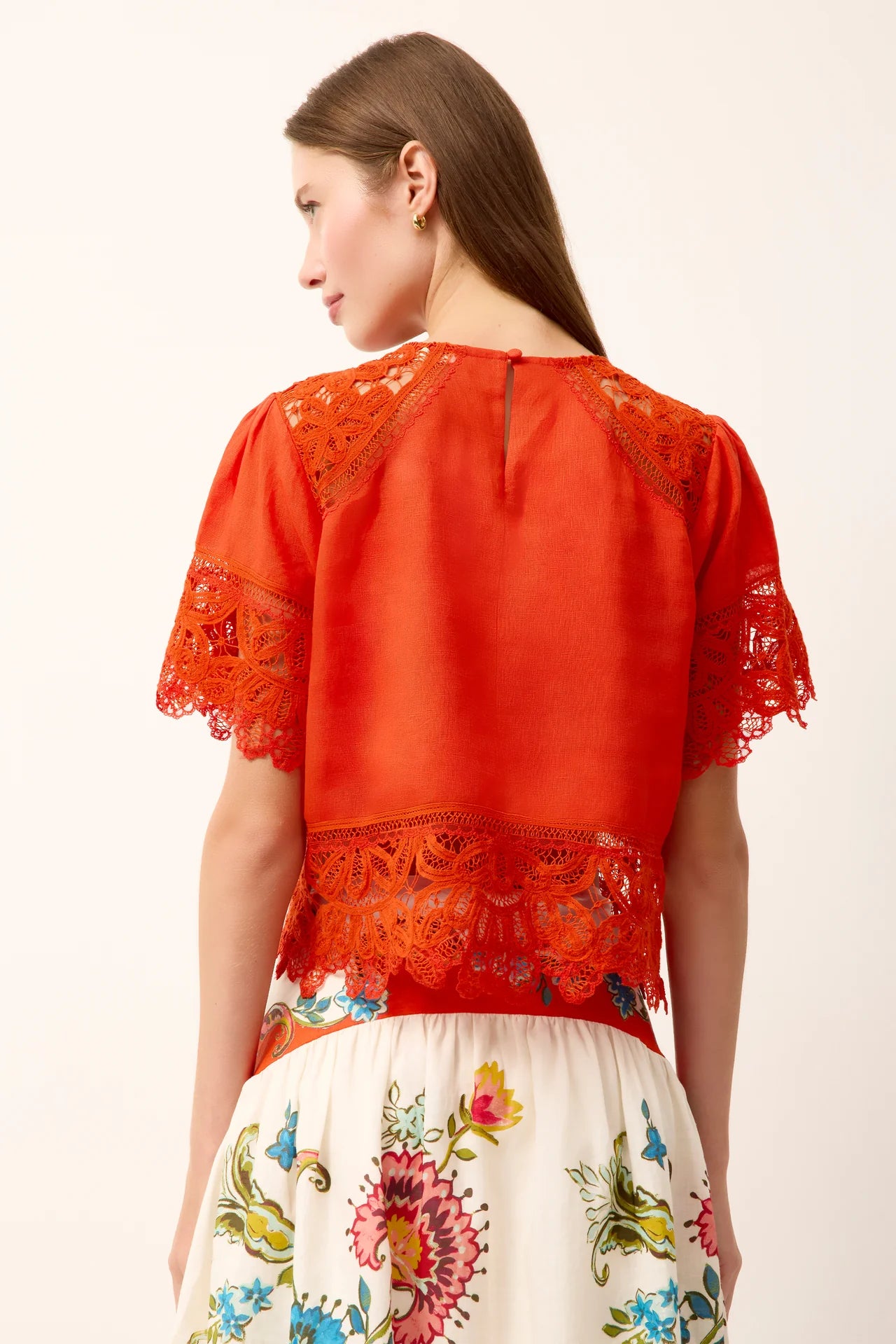 Woman wearing a red blouse with lace details on a white background
