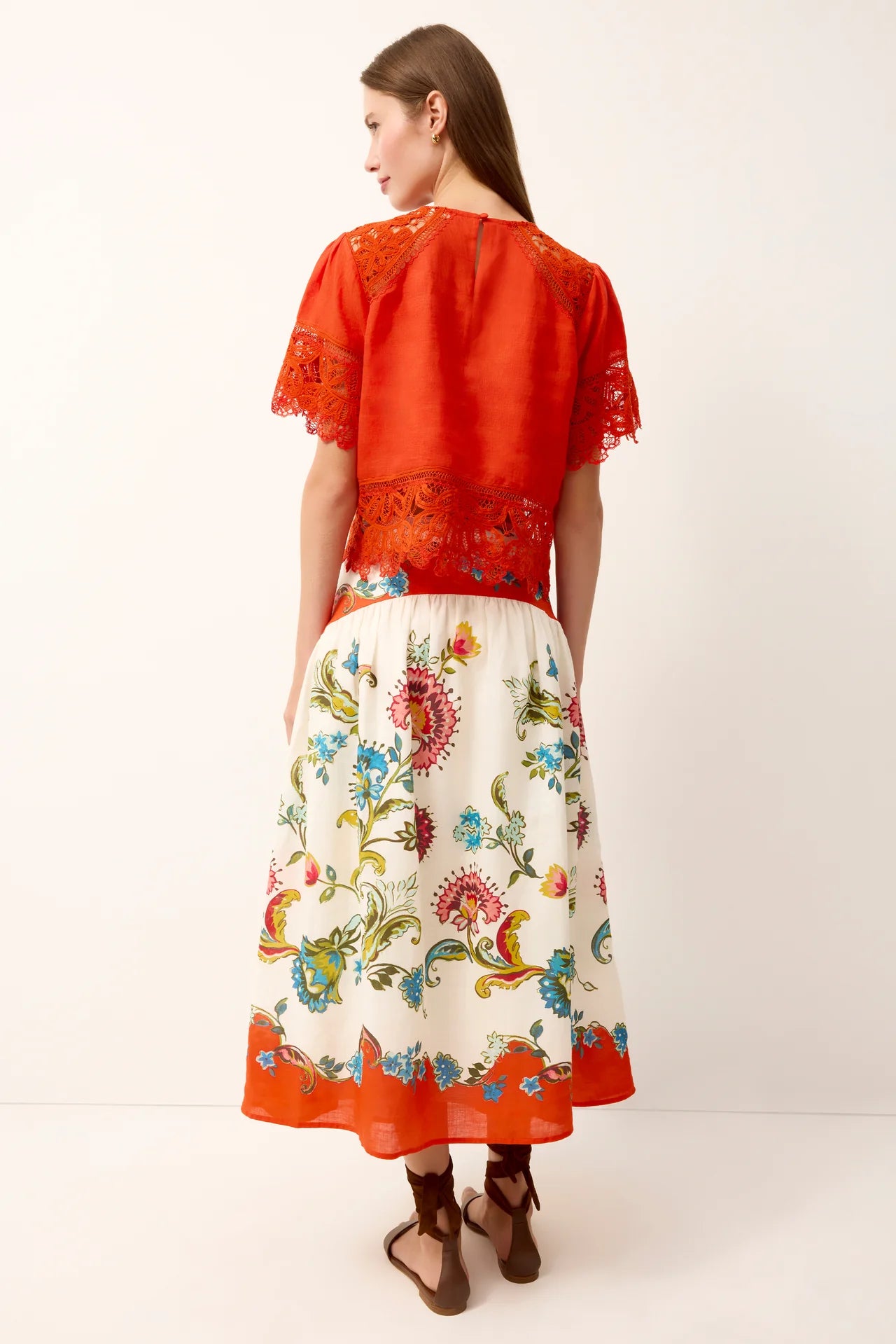 Woman wearing a red top and floral skirt on a white background