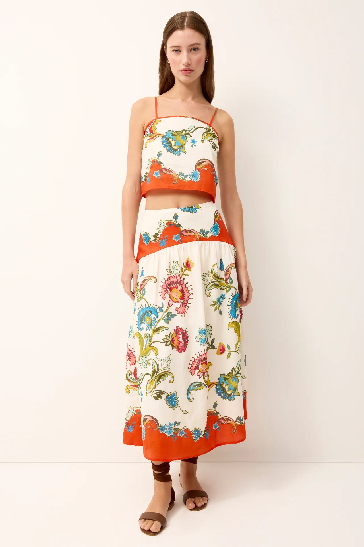 Woman wearing a colorful floral dress with an orange trim on a white background