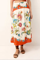 Colorful floral skirt with orange trim worn by a person on a white background